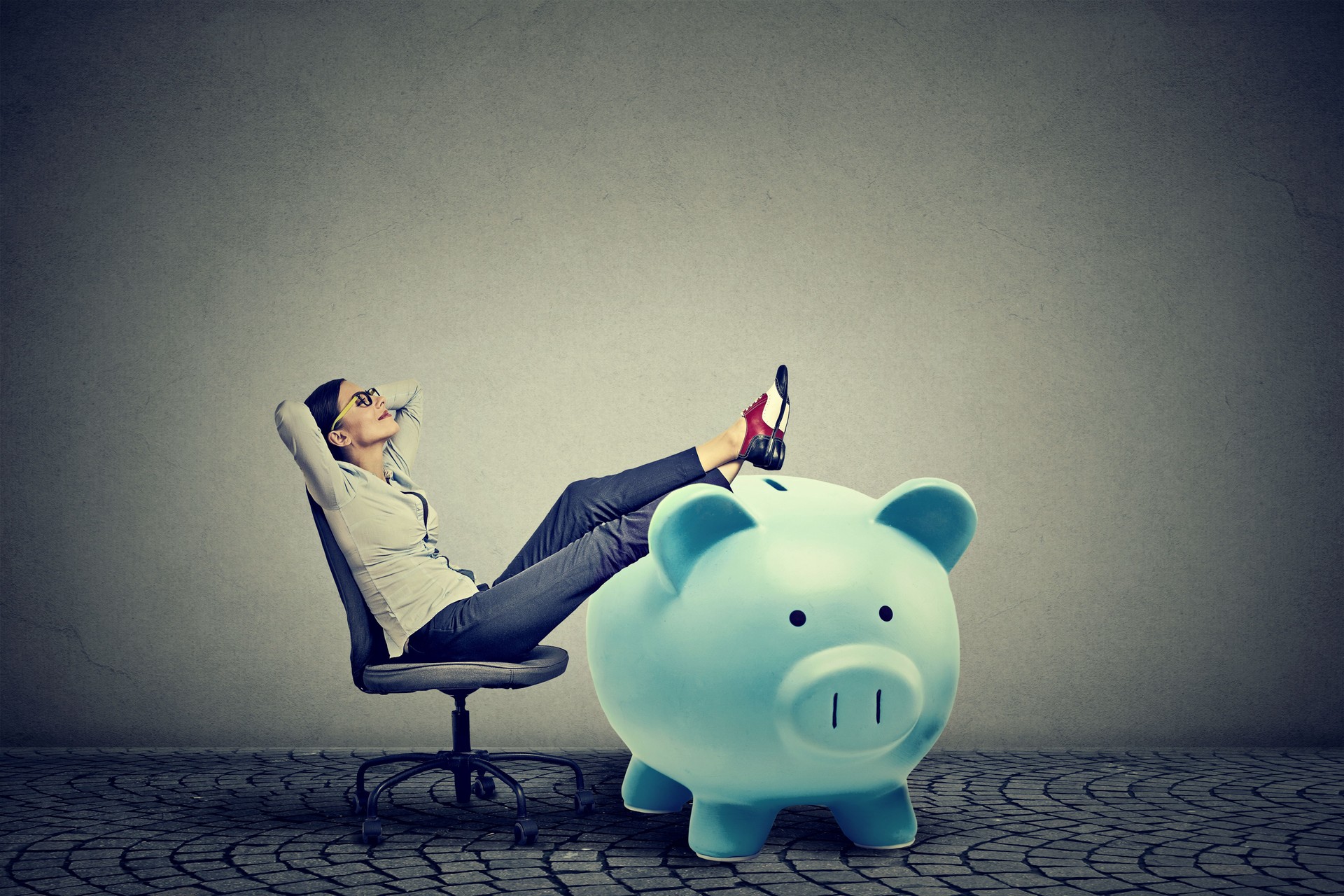 young businesswoman with big piggy bank relaxing sitting on chair